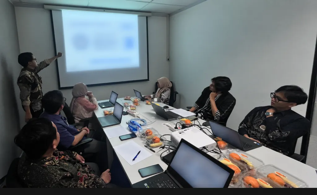 Fakhri presenting the Supplier Performance Review to the meeting; the projected slide is blurred for confidentiality.