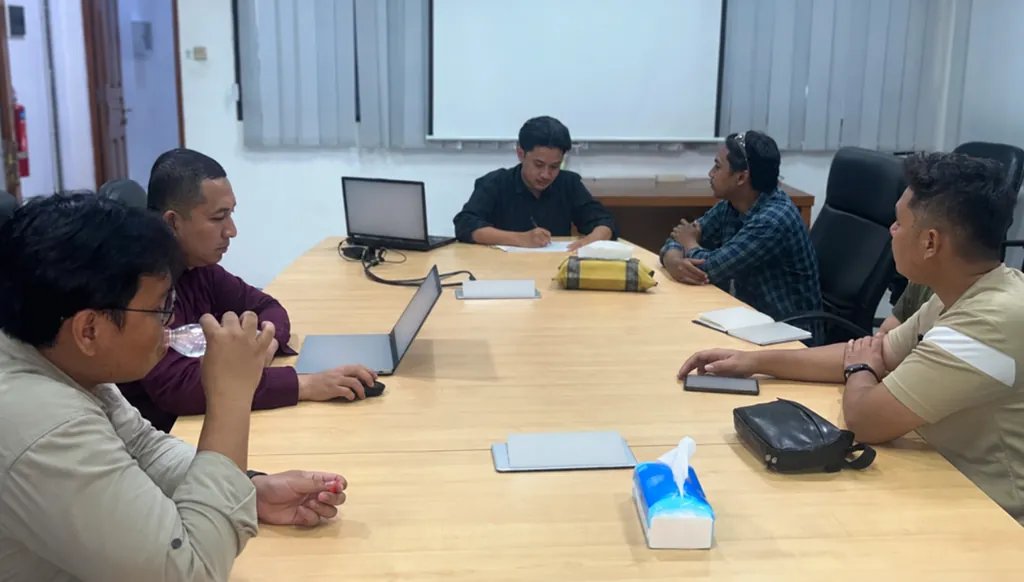 Project team seated around a table reviewing printed documents during a pre-job planning discussion.